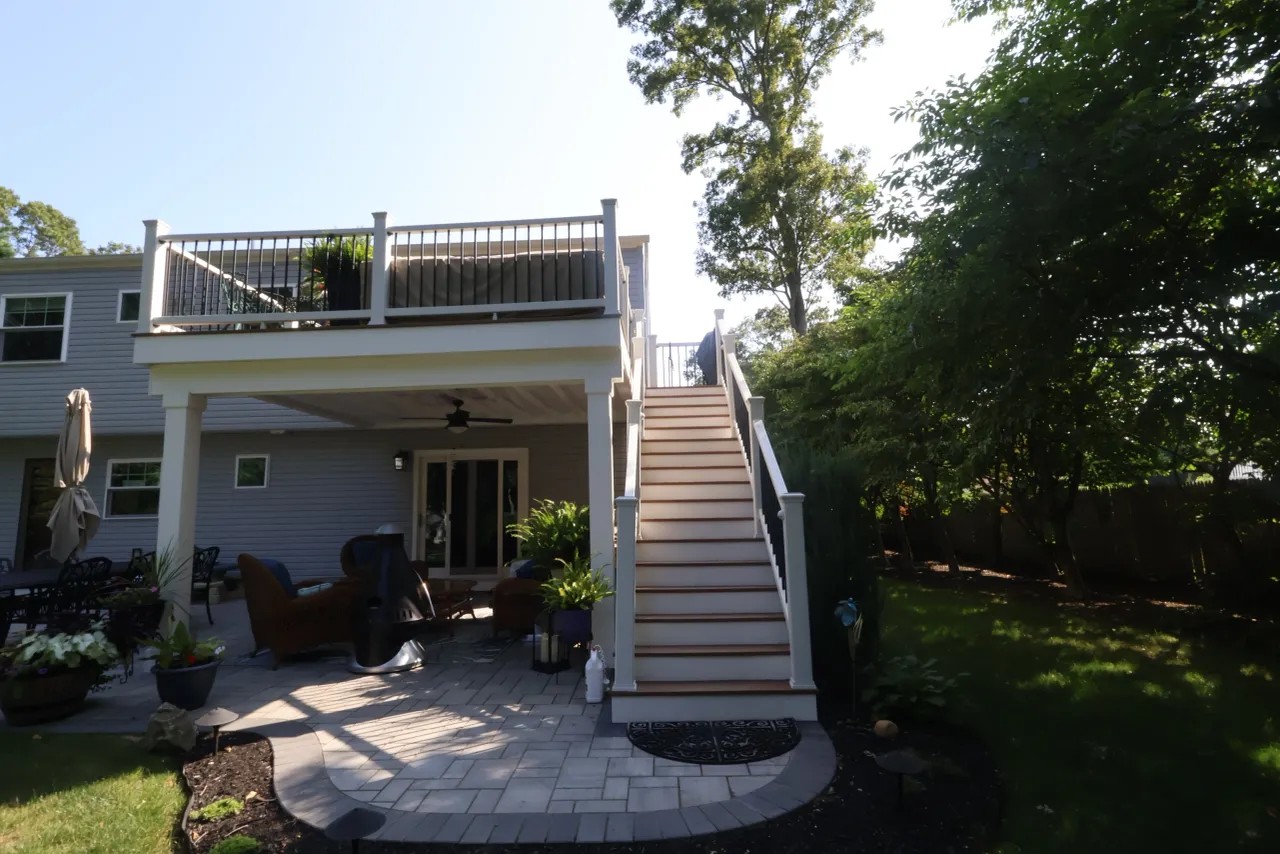 Second-story deck above a covered patio with stairs down to a paver patio