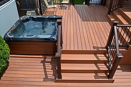 Hot tub set into a wooden deck with steps and matching railing