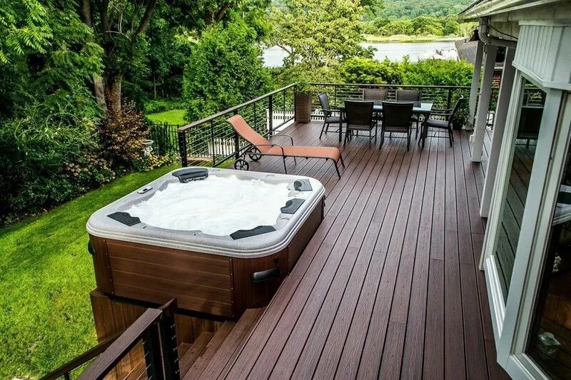 Hot tub on a dark composite deck with lounge chair and water view