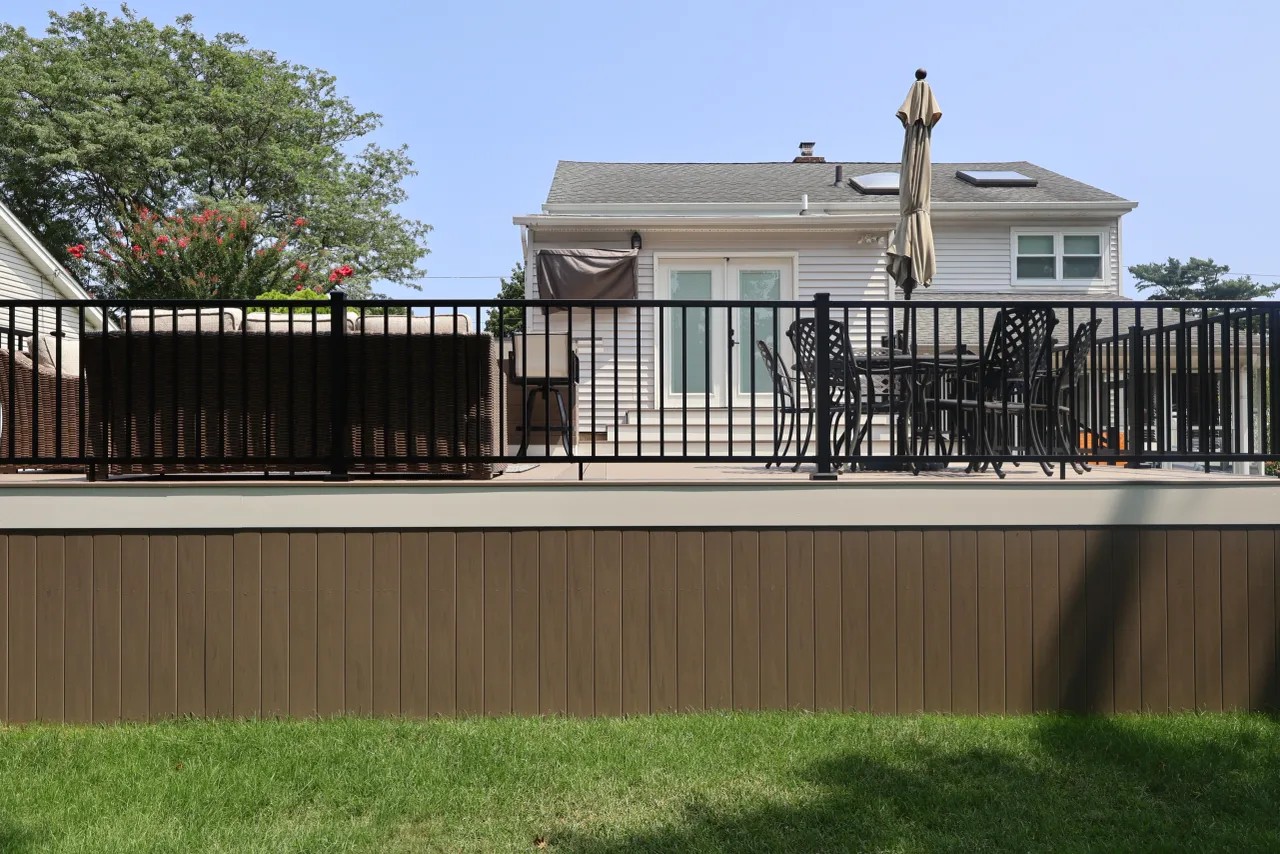 Deck stairs with a self-closing gate and black aluminum railing