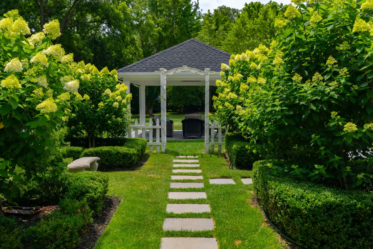 Stepping-stone path through hydrangeas and boxwood to a white gazebo