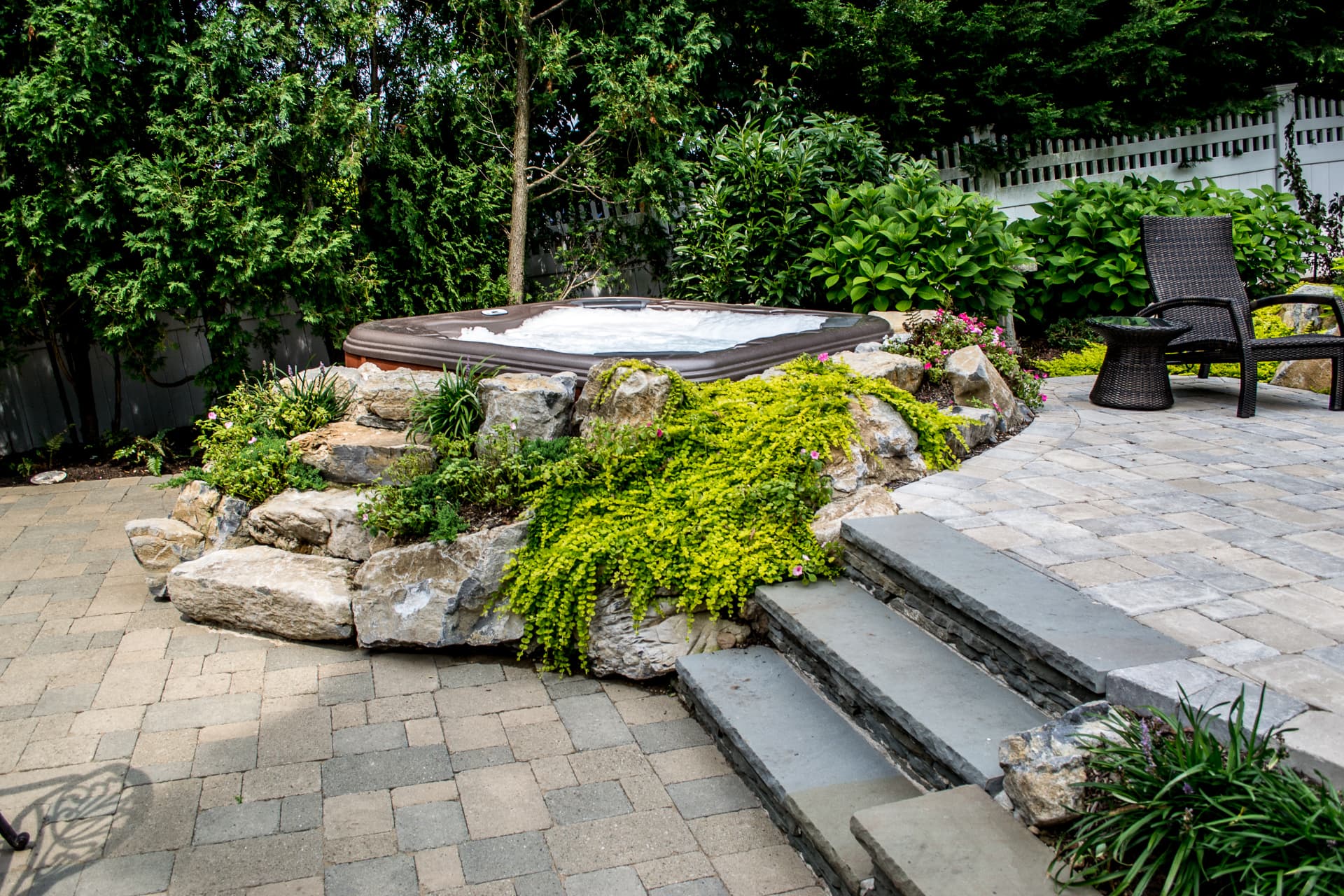 Hot tub terraced into a planted boulder wall with bluestone steps