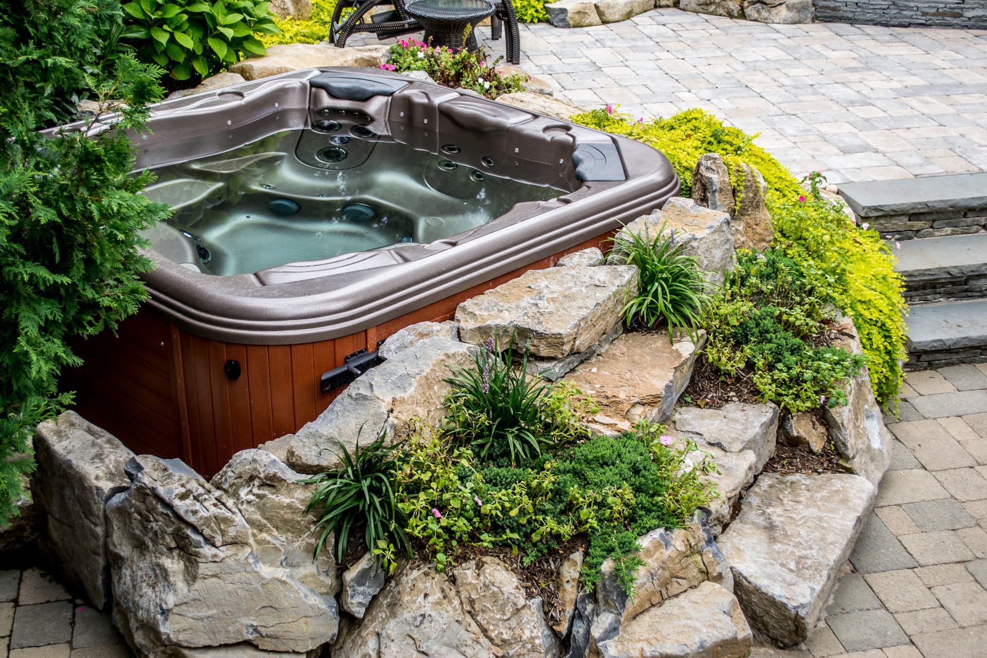 Hot tub tucked into natural boulders and cascading ground cover