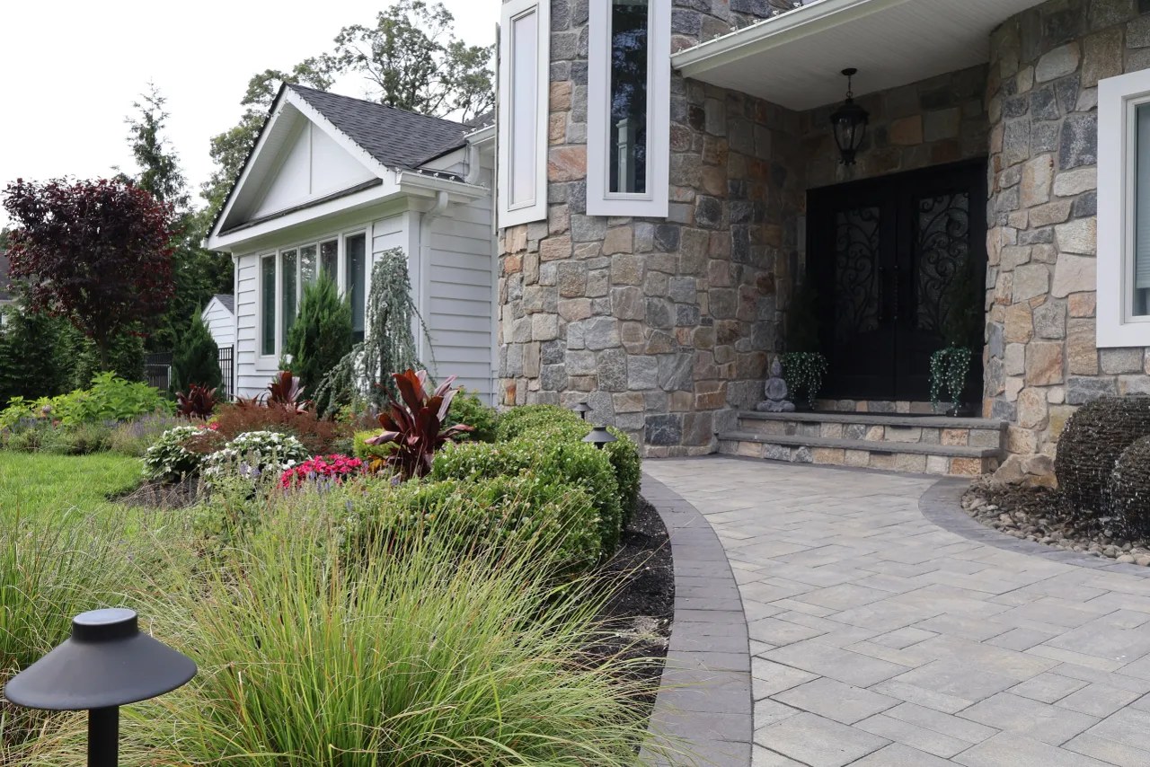 Curving paver walkway past layered plantings to a stone entry