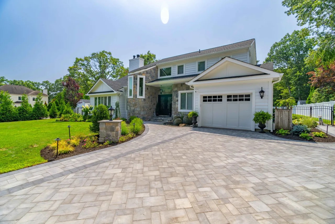 New paver driveway framed with fresh planting beds and lawn
