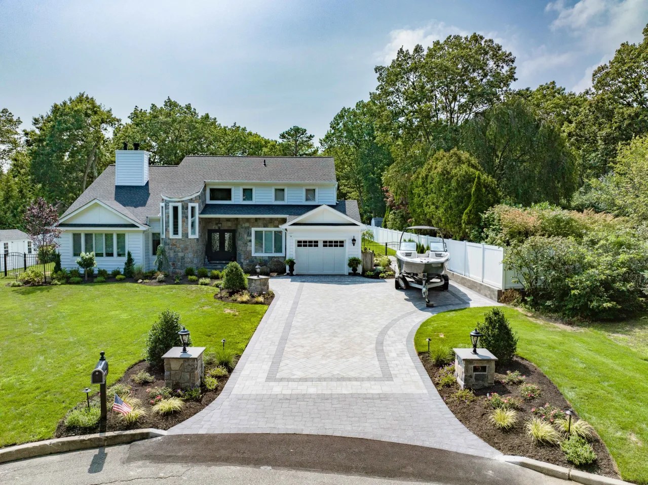 Aerial view of a paver driveway and front landscape with stone piers