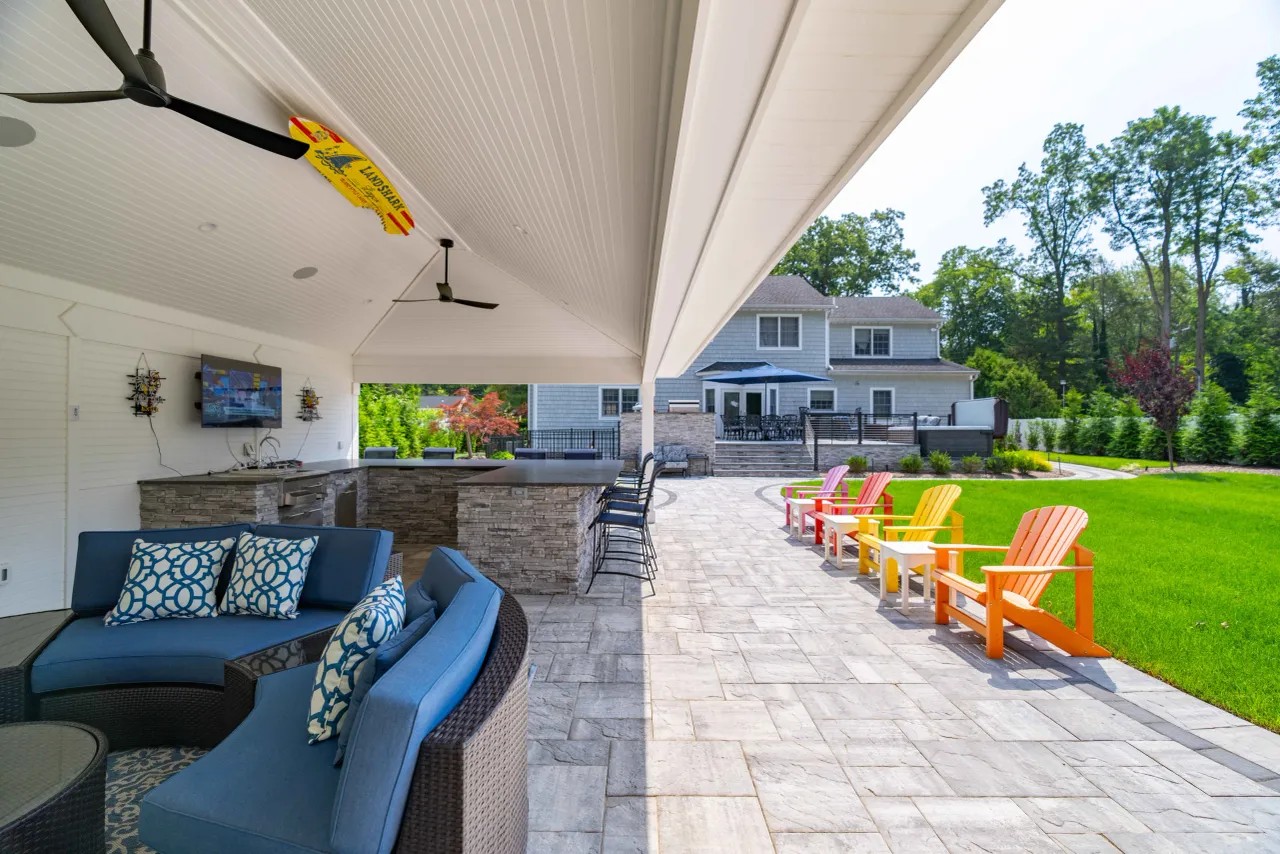 Covered pavilion outdoor living room with stone bar and paver patio