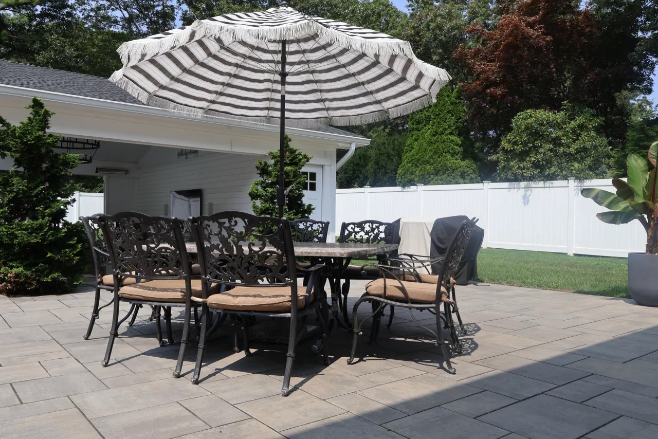 Paver patio dining set with a striped market umbrella