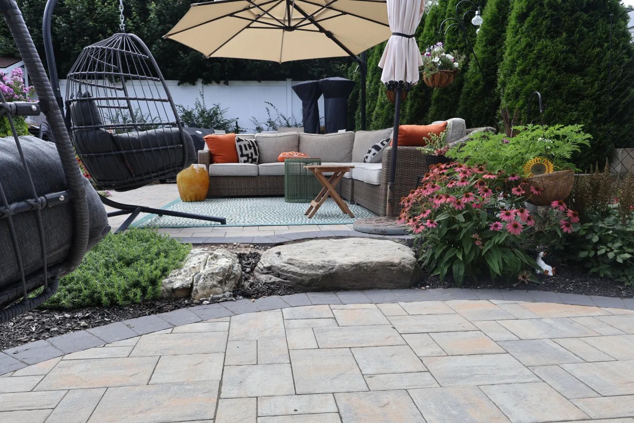Paver patio lounge with sectional seating bordered by boulder plantings