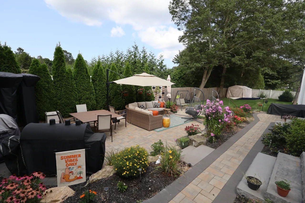 Backyard paver patio with dining set, shade umbrella and curved walkway
