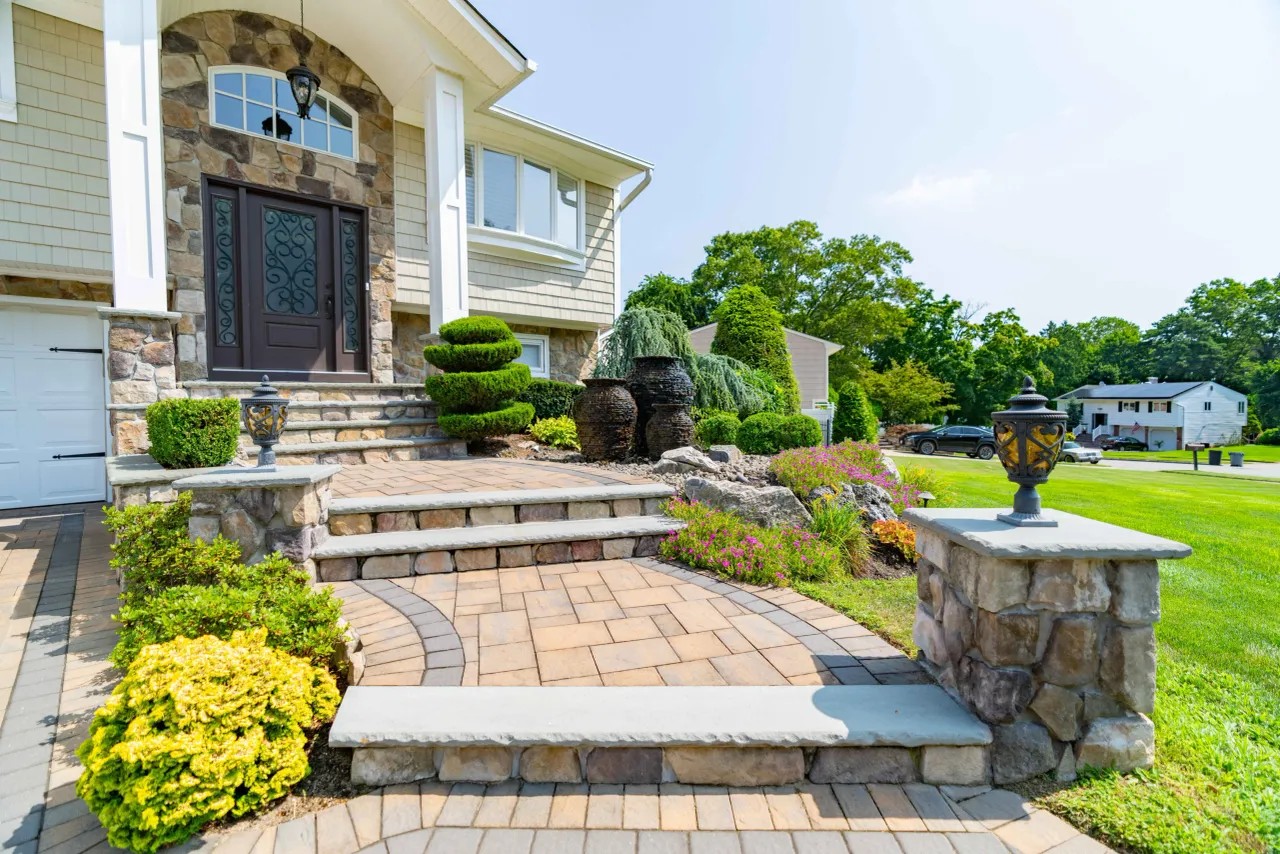 Bluestone entry steps with stone pillars and a paver front walkway