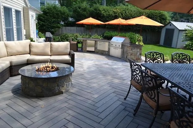 Backyard patio with gas fire pit, curved outdoor bar and orange umbrellas