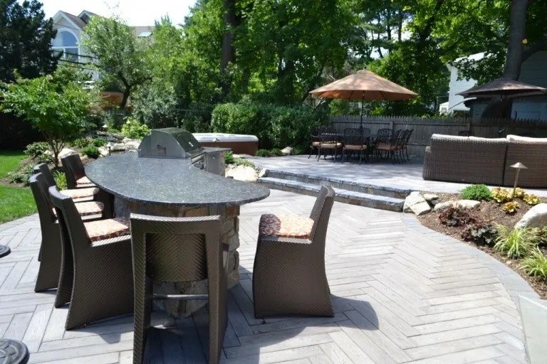 Curved granite-topped bar with bar stools beside a pool on a paver patio