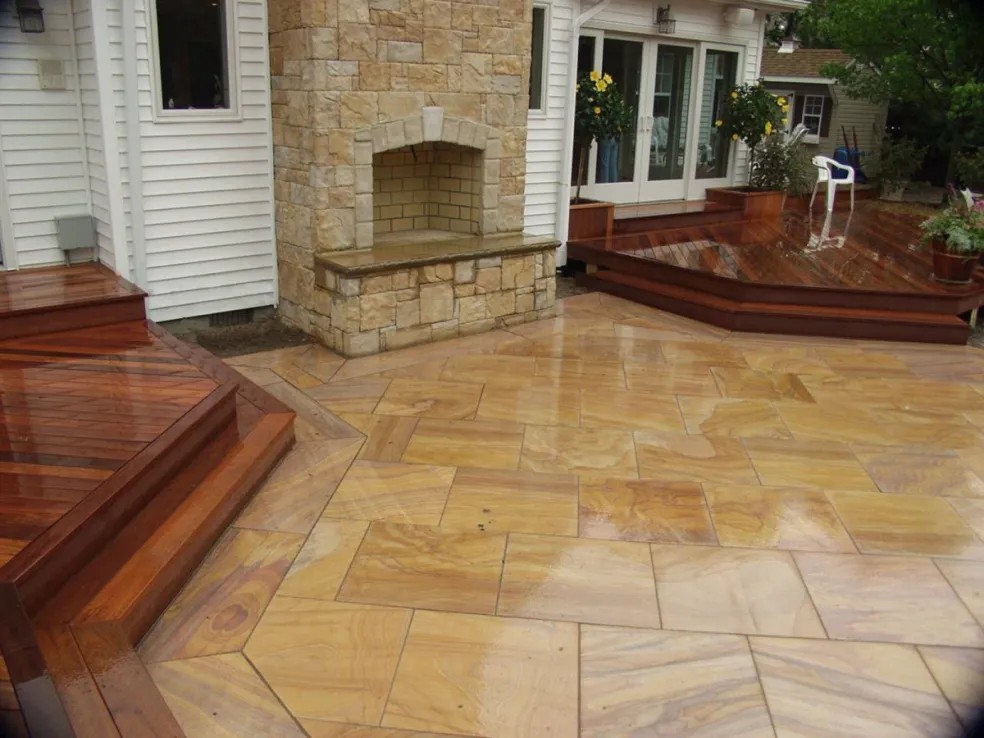 Stone outdoor fireplace with raised hardwood decks and sandstone patio