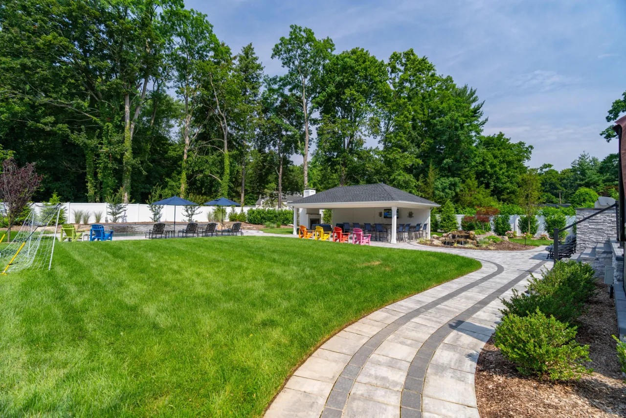 Curved paver walkway with banding leading to a poolside pavilion