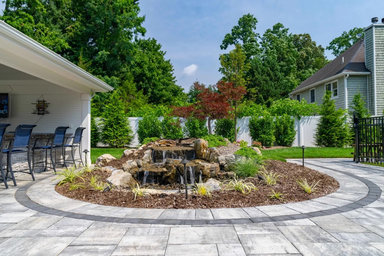 Circular paver patio framing a multi-tiered stone waterfall