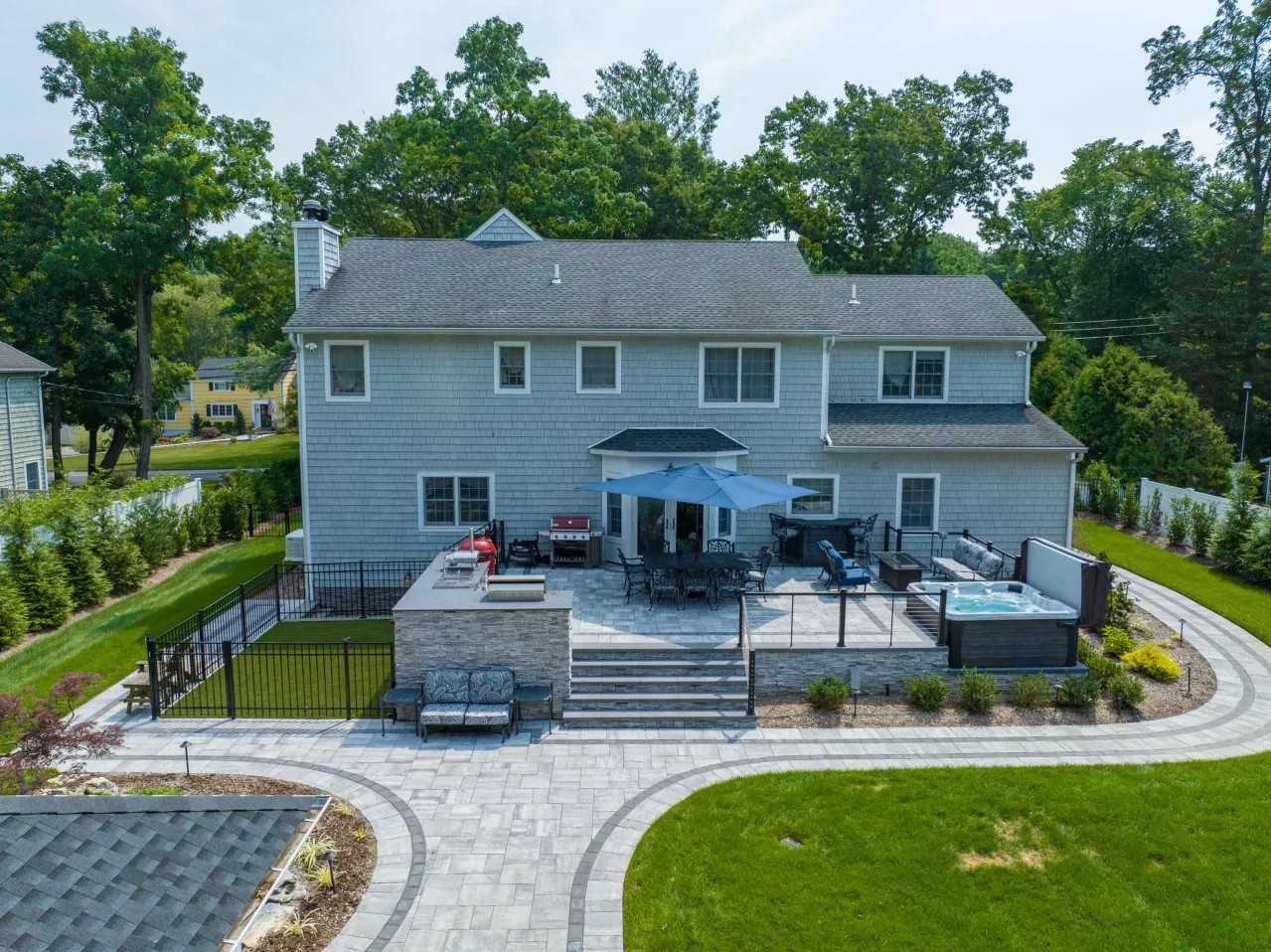 Aerial view of a backyard with paver patio, outdoor kitchen and hot tub
