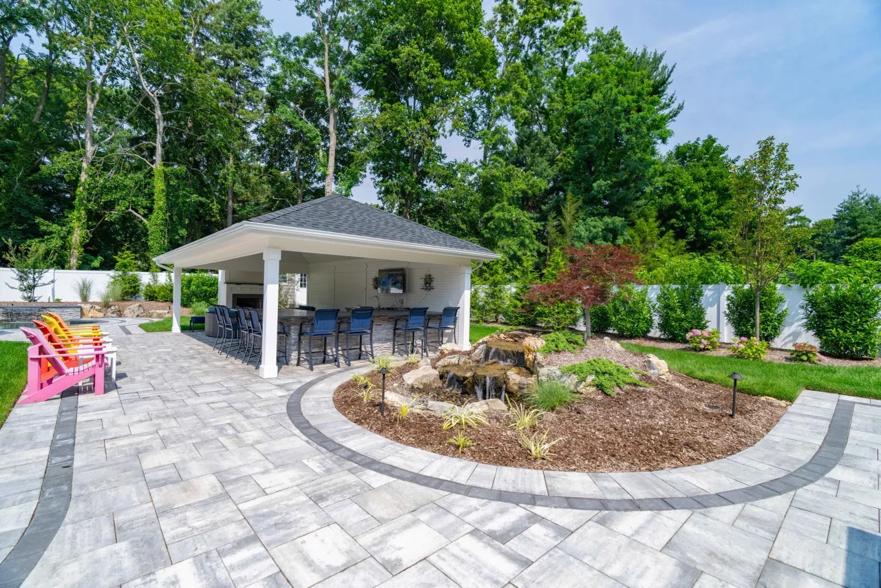 Poolside pavilion with bar seating beside a stone waterfall feature