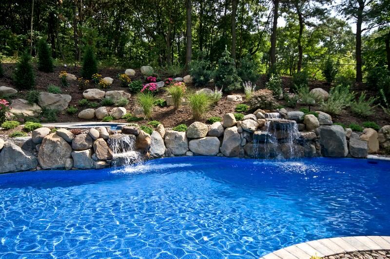Pool with twin rock waterfalls below a planted boulder hillside