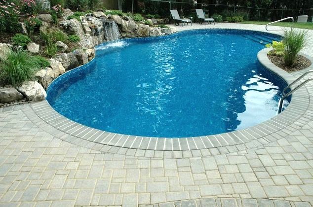 Pool Surround: This pool is surrounded by a patio created from Cambridge’s Round Table pavingstones. The pavers’ dimpled, embossed surfaces gently roll into soft, beveled edges on four straight-sided Cambridge Shapes with ArmorTec. The pavers were laid in a handsome modified herringbone pattern. 