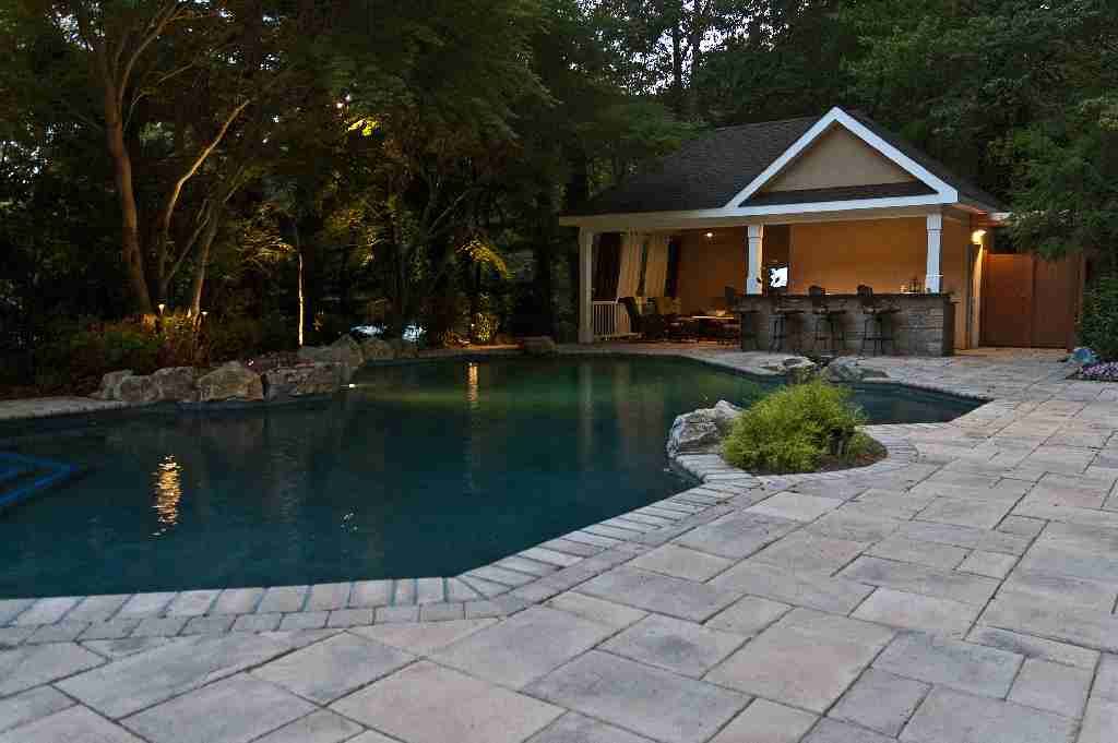 Our outdoor living expert retained and transplanted most of property’s original mature growth trees to create a lush setting for pool and cabana area. Resort-style mood of backyard retreat is at its romantic best at sunset.