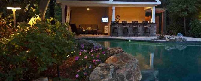 Bright delicate impatiens, moss rock boulders and large mature trees beautifully naturalize original geometric pool area.