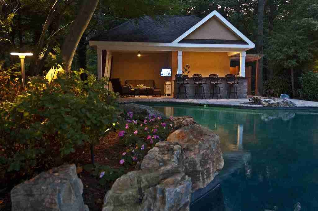Bright delicate impatiens, moss rock boulders and large mature trees beautifully naturalize original geometric pool area.