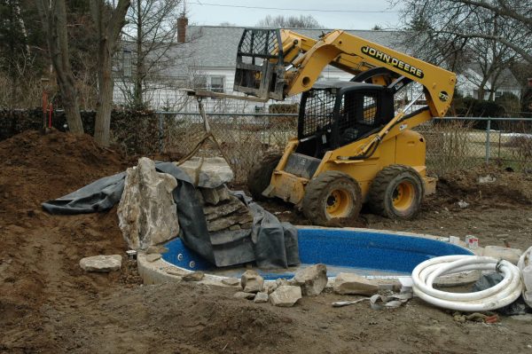 “During” Waterfall Addition: The boulders needed for a good-looking waterfall can weigh tons and special machinery is needed to put them in place. 