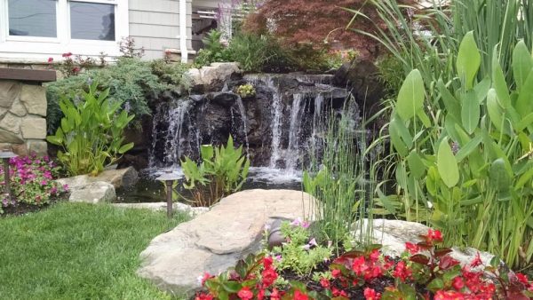 Not all waterfall projects need to be on a grand scale. Even modest projects such as this is an opportunity for natural color, textures, and pleasant sounds. Waterfalls splashing in a pond aerates it, keeping it healthy and mosquito-free. Add some boulders and bright lush plantings and you have a little bit of paradise.